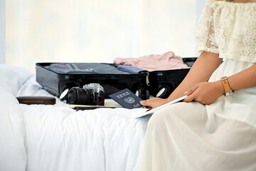 Travel-Ready Woman with Luggage, Passport, and Camera on Bed, Planning Her Next Adventure While Browsing on a Tablet