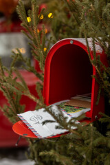 Open red postbox and Christmas postcards and greetings in it, green Christmas tree, red mailbox and letters to Santa Claus © Anna