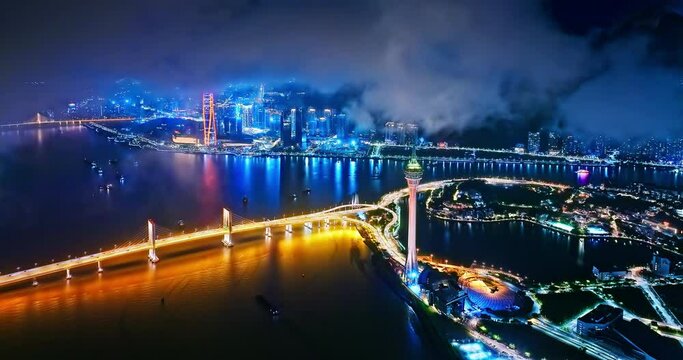 Aerial shot of city buildings and ocean landscape at night in Macau