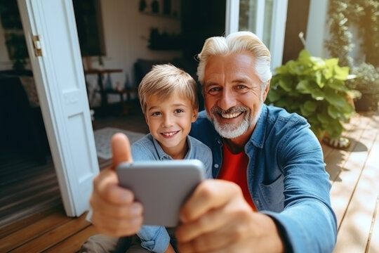 An elderly man uses a smartphone to take selfies of himself and his grandson and learn about social media at home
