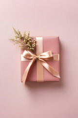 A gift box wrapped in pink paper with ribbon bow and decorated with flowers on pink background