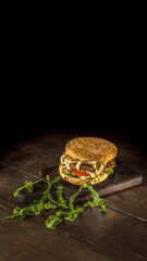 Hamburguer com carne, queijo derretido, alface, tomate sobre fundo de madeira
