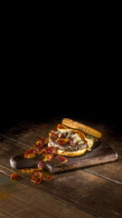 Hamburguer com carne, queijo derretido, cheddar e bacon sobre fundo de madeira