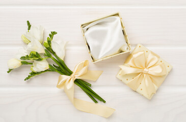 Open gift box, with fresia flower wooden background, top view