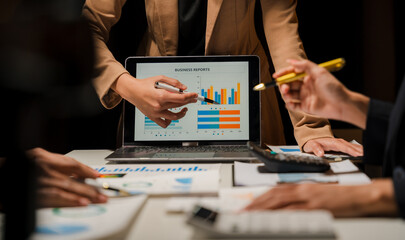 Group of confident business people point to graphs and charts to analyze market data, balance sheet, account, net profit to plan new sales strategies to increase production capacity. - Powered by Adobe