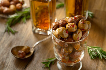 Spicy olives and bottles of olive oil on a wooden table.