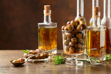 Spicy olives and bottles of olive oil on a wooden table.