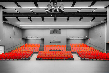 Photo of a new school theater, auditorium, with red and gray seats, chairs and new carpet in the...