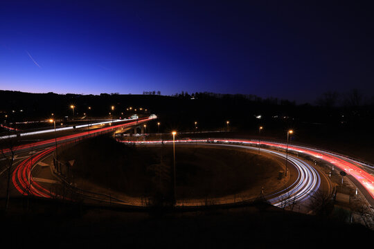 long exposure image of a round highway entrance at night time with a lot of car light trails