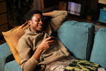 African American dark skinned artist brainstorming new ideas for his next project while lounging on the sofa.