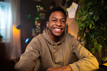 Cozy living room, the African man raises his fists in victory, signifying dark skinned business...