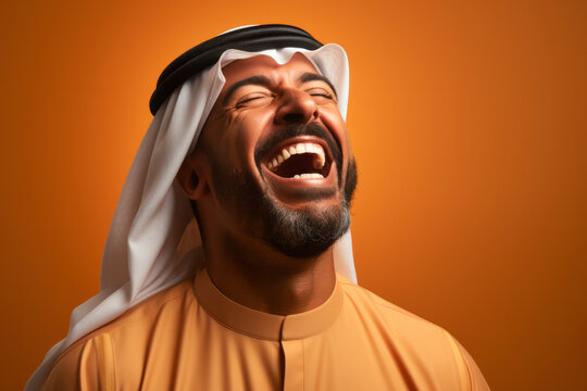 Portrait of happy Saudi young man smiling opening his mouth with joy standing over yellow orange background.