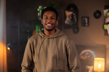 Portrait of delighhted african american man wearing casual hoodie standing in the cozy beautiful...