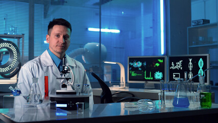 Male scientist sitting in a research lab. A doctor in a white coat looking seriously into the...