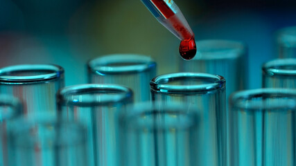 Macro shot of glass test tubes. A drop of red liquid or blood drips from the pipette. Concept of a...