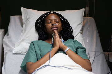 Female patient in hospital ward lies on bed prays looking at ceiling she is worried before surgery