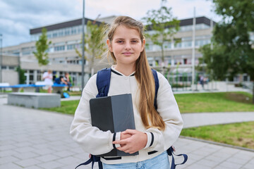Portrait of smiling schoolgirl child with backpack digital tablet outdoor