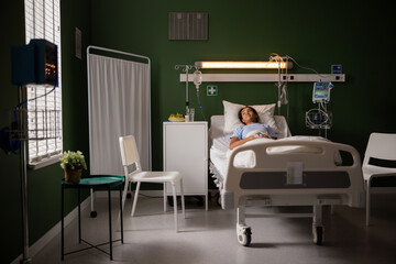 Child in hospital ward lays on bed, looking out the window.