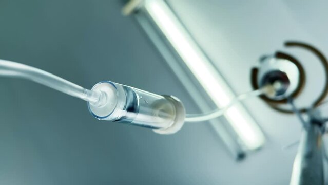 Drip chamber of a IV with dropper bottle on a stand. Intravenous injections, medical care in a clinic. Recovering patient. Bottom up. Wide angle view. Closeup. Vertical video