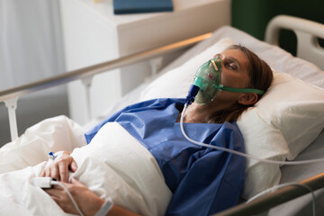 Portrait of elderly patient in hospital bed, with oxygen mask, resting getting treatment.
