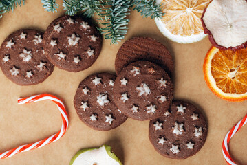 Christmas gingerbreads, candy cane, dried fruits and baubles on kraft paper background. Top view, flat lay