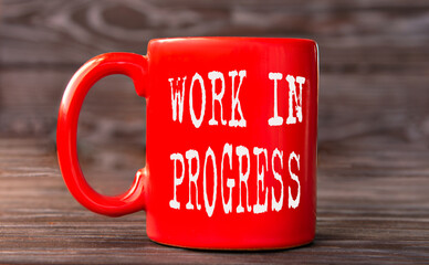 WORK IN PROGRESS - words on a red cup on a dark background.