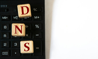 Obraz premium DNS - acronym on wooden cubes against the background of a calculator. Copy space