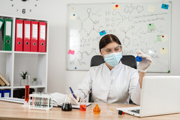 Caucasian female pharmacist in lab coat looking on reagents in test tube