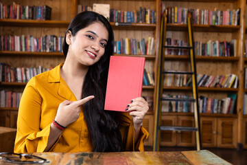 A beautiful young girl business woman or student working or studying in school or collage library...