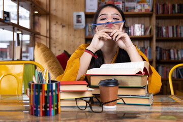 A beautiful young girl business woman or student seating with pile of books working or studying in school or collage library or in corporate office sitting with books
