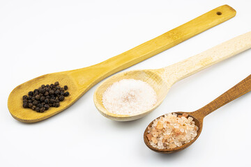 Three spoonfuls of salt and black pepper isolated on a white background