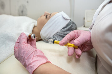 closeup of cosmetologist hand doing treatment procedure with injecting botox in woman client face