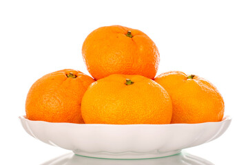 A few sweet tangerines in a white ceramic plate, macro, isolated on a white background.