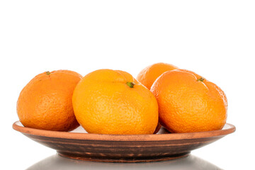 A few sweet tangerines in a clay plate, macro, isolated on a white background.