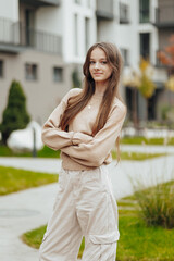 Vertical photo. Beautiful carefree young teenage girl in casual clothes. Portrait of a beautiful girl against the background of nature with a blurred background.