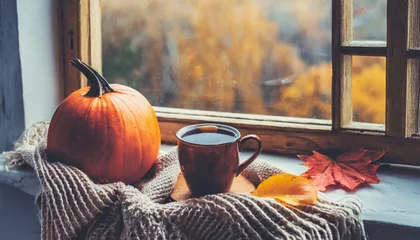 Zelfklevend Fotobehang cup of hot autumn coffee or tea on the window living in hygge style hot drink in cold autumn fall weather halloween © Kendrick