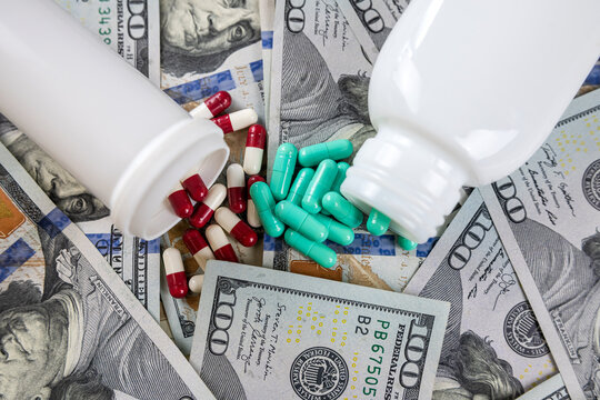 Open  jar or bottle with pills lying on dollar bills background