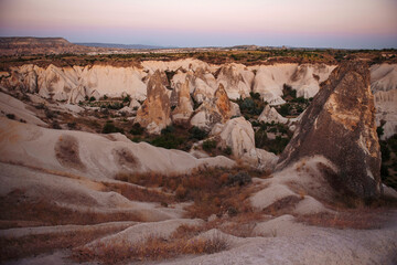 Fototapeta na wymiar Amazing sunset view with tuff rock formation in Turkey, Cappadocia. Beautiful desert and valley during summer time.