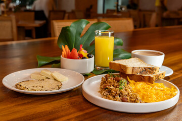 Colombian breakfast with arepas, coffee, bread, eggs, warmed rice and fruit