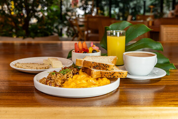 Colombian breakfast with arepas, coffee, bread, eggs, warmed rice and fruit