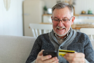 Senior man shopping online holding smartphone paying with credit card. Old grandfather buying on...