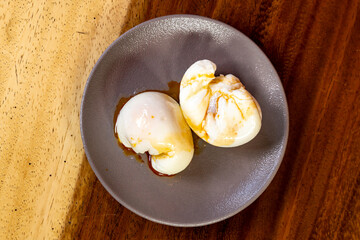 two poached eggs on a plate with olive vegetable oil