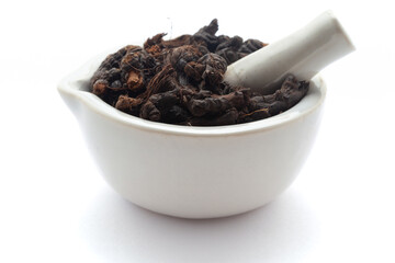 Close-up of Dry organic Nagarmotha (Cyperus scariosus) roots, in white ceramic mortar and pestle, isolated on a white background.