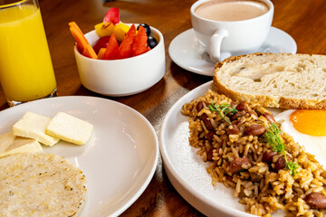 Colombian breakfast with arepas, coffee, bread, eggs, warmed rice and fruit