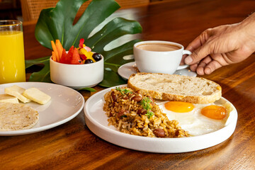 Colombian breakfast with arepas, coffee, bread, eggs, warmed rice and fruit