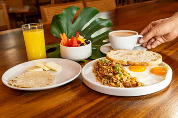 Colombian breakfast with arepas, coffee, bread, eggs, warmed rice and fruit