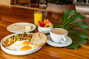Colombian breakfast with arepas, coffee, bread, eggs, warmed rice and fruit