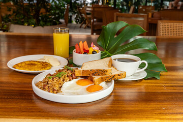 Colombian breakfast with arepas, coffee, bread, eggs, warmed rice and fruit
