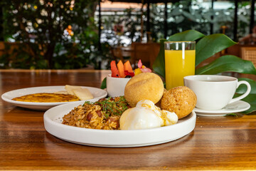 Colombian breakfast with arepas, coffee, bread, eggs, warmed rice and fruit