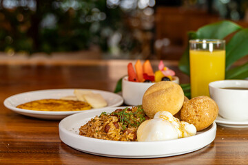 Colombian breakfast with arepas, coffee, bread, eggs, warmed rice and fruit